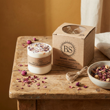 Medium handmade Rose Petals candle on a wooden table with scenic countryside view