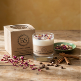 Glass candle with dried flowers and cinnamon sticks on a wooden surface, branded 'Beauty Scents'.