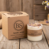 Candle with decorative elements and 'BS beauty scents' packaging on a wooden surface