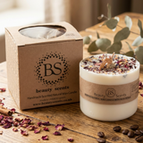 Beauty Scents Large Candle With Rose Petals with next to its box on the wooden table surounded with dried rose petals and coco beans