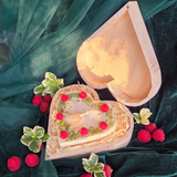 Large heart-shaped candle with raspberry decorations in a wooden heart gift box