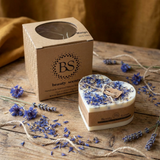 HEART SHAPED CANDLE WITH BLUE FLOWERS ON WOODEN TABLE IN COUNTRY SIDE BACKGROUND