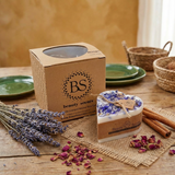 Heart-shaped candle with 'BS Beauty Scents' branding on a wooden table with lavender and cinnamon sticks.