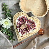 Large heart-shaped candle with rose petals in a wooden heart gift box