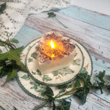 Heart-shaped candle on a decorative plate with greenery on a rustic wooden surface